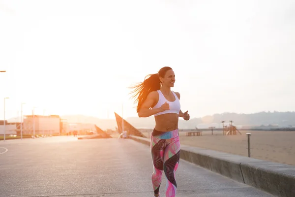 Cheerful fitness woman running at sunset — Stock Photo, Image