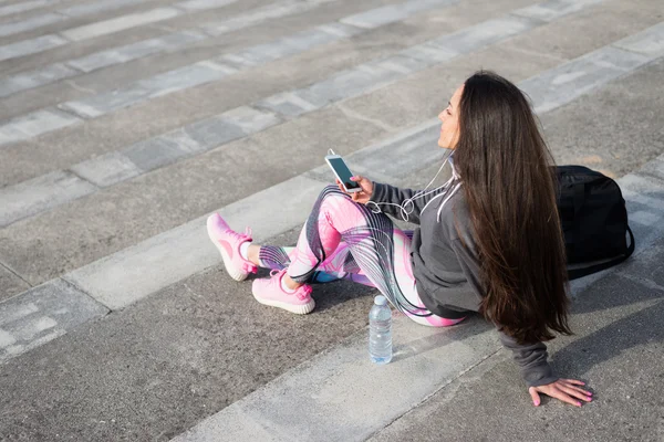 Спортивная женщина отдыхает на тренировке для прослушивания музыки на смартпе — стоковое фото