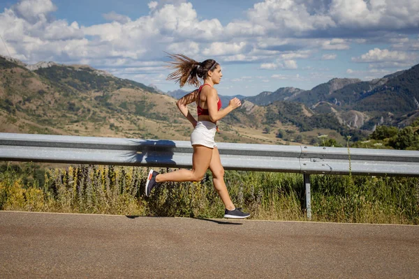 夏天适合女运动员在山路斜坡上跑步 体形瘦小的女人夏天在户外刻苦训练 — 图库照片