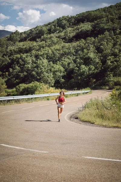 夏天适合女运动员在山路斜坡上跑步 体形瘦小的女人夏天在户外刻苦训练 — 图库照片