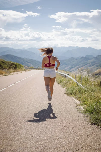 夏季在山路上跑步的女运动员的回顾 — 图库照片
