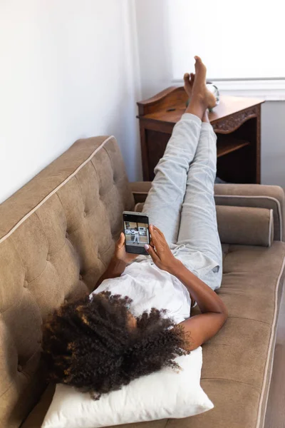 Mulher Negra Relaxada Deitada Seu Sofá Usando Seu Smartphone Relaxante — Fotografia de Stock