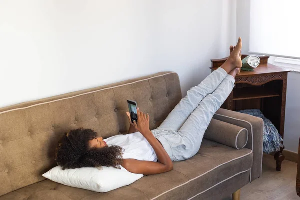 Mulher Negra Relaxada Deitada Seu Sofá Usando Seu Smartphone Relaxante — Fotografia de Stock