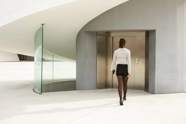 Trendy modern businesswoman entering corporate building — Stock Photo, Image