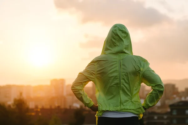 Athlete looking sunset over city skyline after exercising — Stock Photo, Image