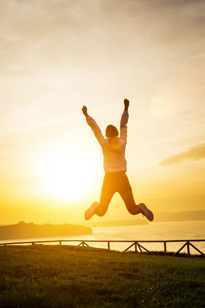 Lyckliga kvinnliga idrottare hoppa mot solen — Stockfoto