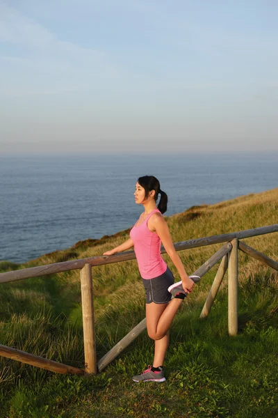 Atleta feminina se alongando após correr e se exercitar — Fotografia de Stock