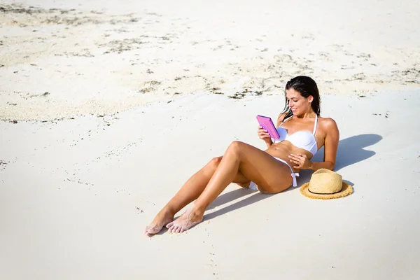 Žena, čtení e knihy na pláži — Stock fotografie
