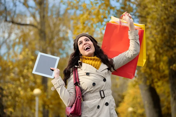 Счастливая женщина делает покупки и держит в руках цифровой планшет — стоковое фото