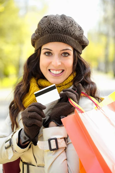 Mulher com sacos de compras e cartão de crédito no outono — Fotografia de Stock