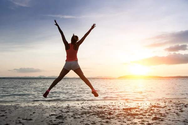 Sporty woman jumping on sunset at the beach. — Stock Photo, Image