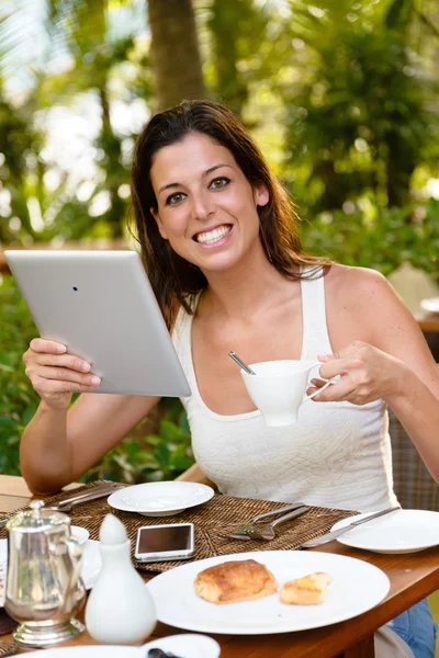 Femme heureuse prenant le petit déjeuner et utilisant une tablette numérique — Photo