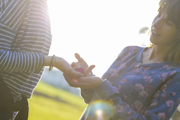 Ung kvinna ger en delikat liten blomma till sin flickvän — Stockfoto