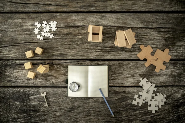 Différents cubes, chevilles, puzzles et une clé couché sur arou bureau en bois — Photo