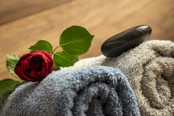 Red rose and black zen massage stone on blue and white rolled to — Stock Photo, Image