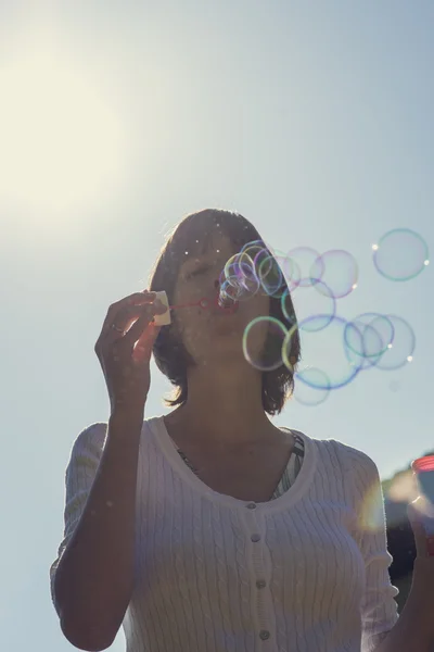 Jeune femme soufflant bulles de savon — Photo