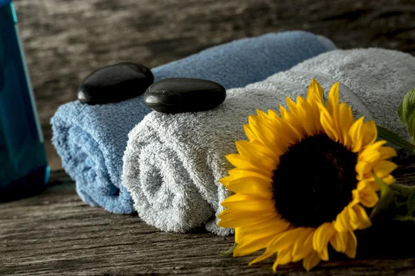 Two rolled towels with black zen stones on them and a beautiful — Stock Photo, Image