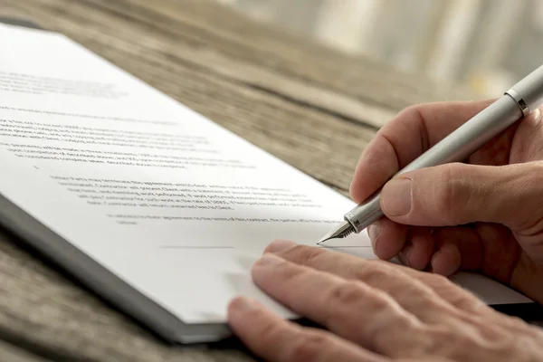 Fecho da mão masculina que assina um contrato ou formulário de candidatura — Fotografia de Stock