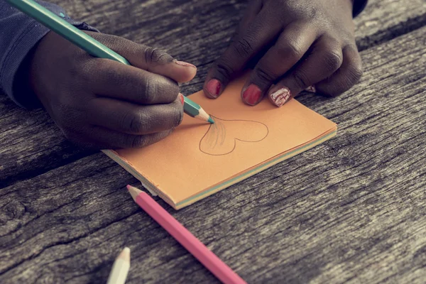 Primo piano di afro-americano ragazza disegno e colorazione un cuore sh — Foto Stock