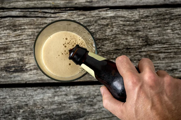 Vista superior de la mano masculina vertiendo cerveza oscura en un vaso —  Fotos de Stock