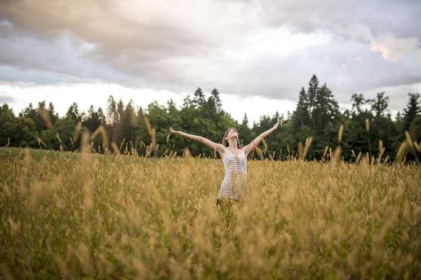 Молодая женщина наслаждается жизнью в красивой природе стоя с ней — стоковое фото
