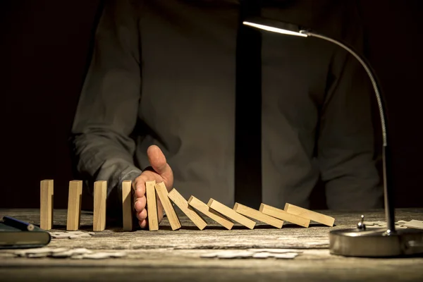 Vooraanzicht van zakenman stoppen vallende dominos met zijn hand — Stockfoto