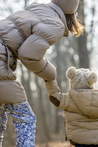 Genç anne onu yürümeye başlayan çocuk po için eğilerek arkadan görünümü