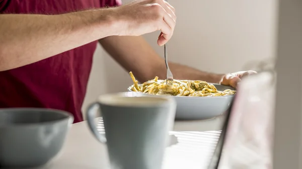 Fechar-se de um homem rodopiando espaguete com molho de pesto com um garfo — Fotografia de Stock