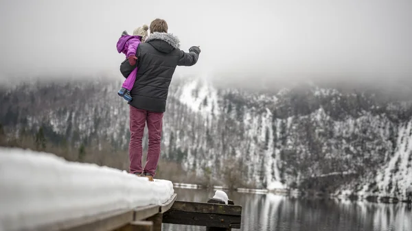 Junger Vater steht am Ende einer verschneiten Seebrücke in einem Holdi-See — Stockfoto