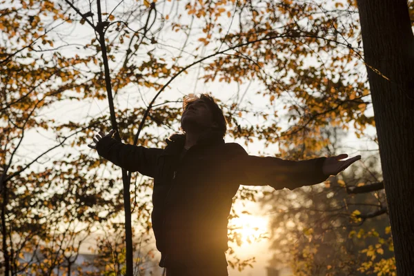 Young man in winter jacket standing with his arms spread widely — 图库照片