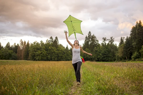Young woman flying a green kite — Stock fotografie