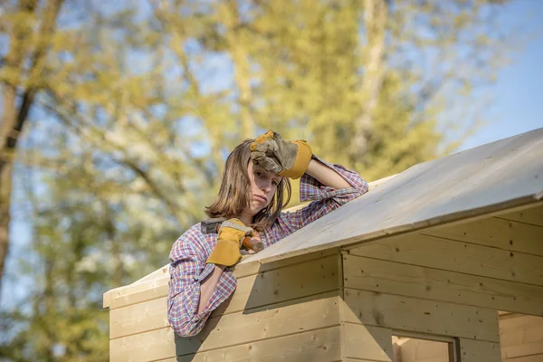 Exhuasted woman working on roof of tree house — Stock Photo, Image