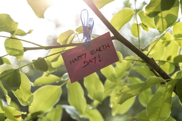 Pale pink coloured piece of paper holding a sign Happy Earth day — Stock Photo, Image