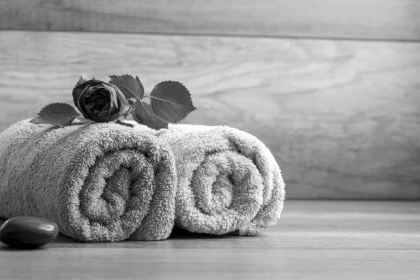 Svart-hvitt bilde av to rullede håndklær med en rose liggende på – stockfoto