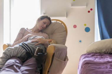 Bir sallanan sandalye üzerinde bebek uyku dinlenme yorgun genç anne