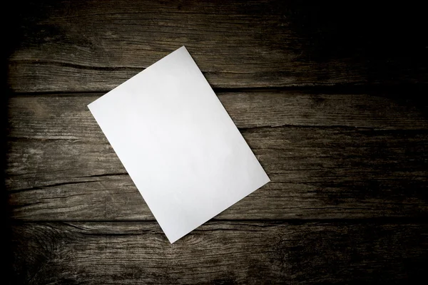 Vue du dessus d'une feuille vierge de papier blanc couchée sur un rusti en bois — Photo