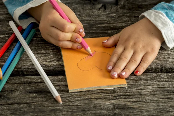 Menina da criança colorir uma forma de coração — Fotografia de Stock