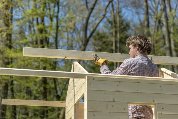 Joven colocando la viga principal de madera para montar un techo de una w — Foto de Stock