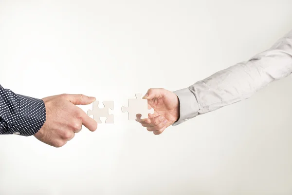 Two businessmen holding out puzzle pieces — Stock Photo, Image