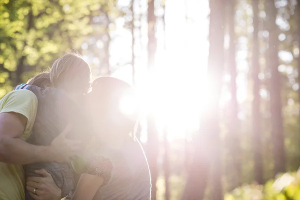 Famille dans les bois embrassant avec la lumière du soleil — Photo