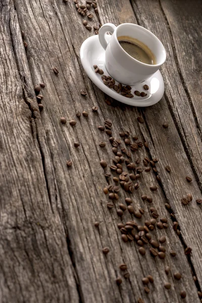 Café com grãos derramados na mesa de madeira — Fotografia de Stock