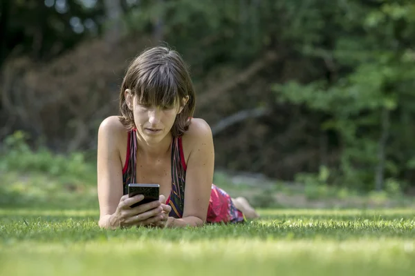 Vuxen kvinna om på gräs med digital reader — Stockfoto