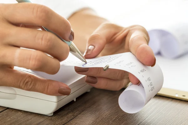 Woman circling numbers on paper receipt — Stock Photo, Image