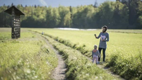 Mère avec son enfant soufflant des bulles de savon dans la nature — Photo