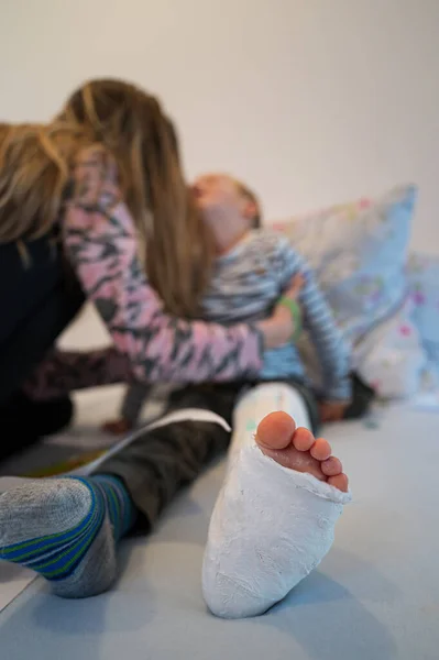 Madre Colocando Hijo Pequeño Con Una Pierna Lesionada Rota Yeso — Foto de Stock