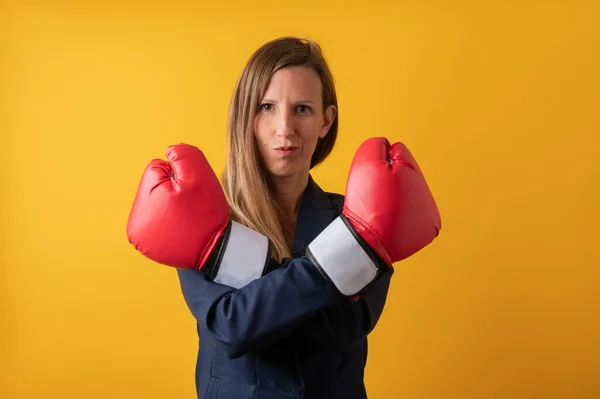 若いビジネスの女性が赤いボクシングの手袋で彼女の手を渡って確信しています 黄色の背景に — ストック写真