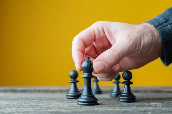 リーダーシップと力の概念的なイメージで他人の前で黒のチェスの図を配置男性の手 — ストック写真