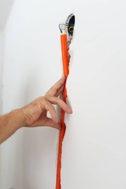 İnşaat görüntüsünde turuncu kıvrımlı kablo kanalını bir duvara yerleştirmek.