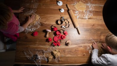 İki çocuğun vejetaryen kurabiye hamuru ve çeşitli şekillerde kesicilerle tatil kurabiyeleri yaptığı en iyi manzara..