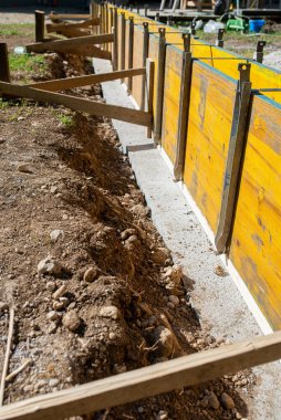 Dışarıdaki inşaat alanında, ahşap panellerden oluşan bir çerçeve çimentoya dökülmeye hazır..